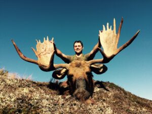 Hunter behind a bull moose on a rocky ridge